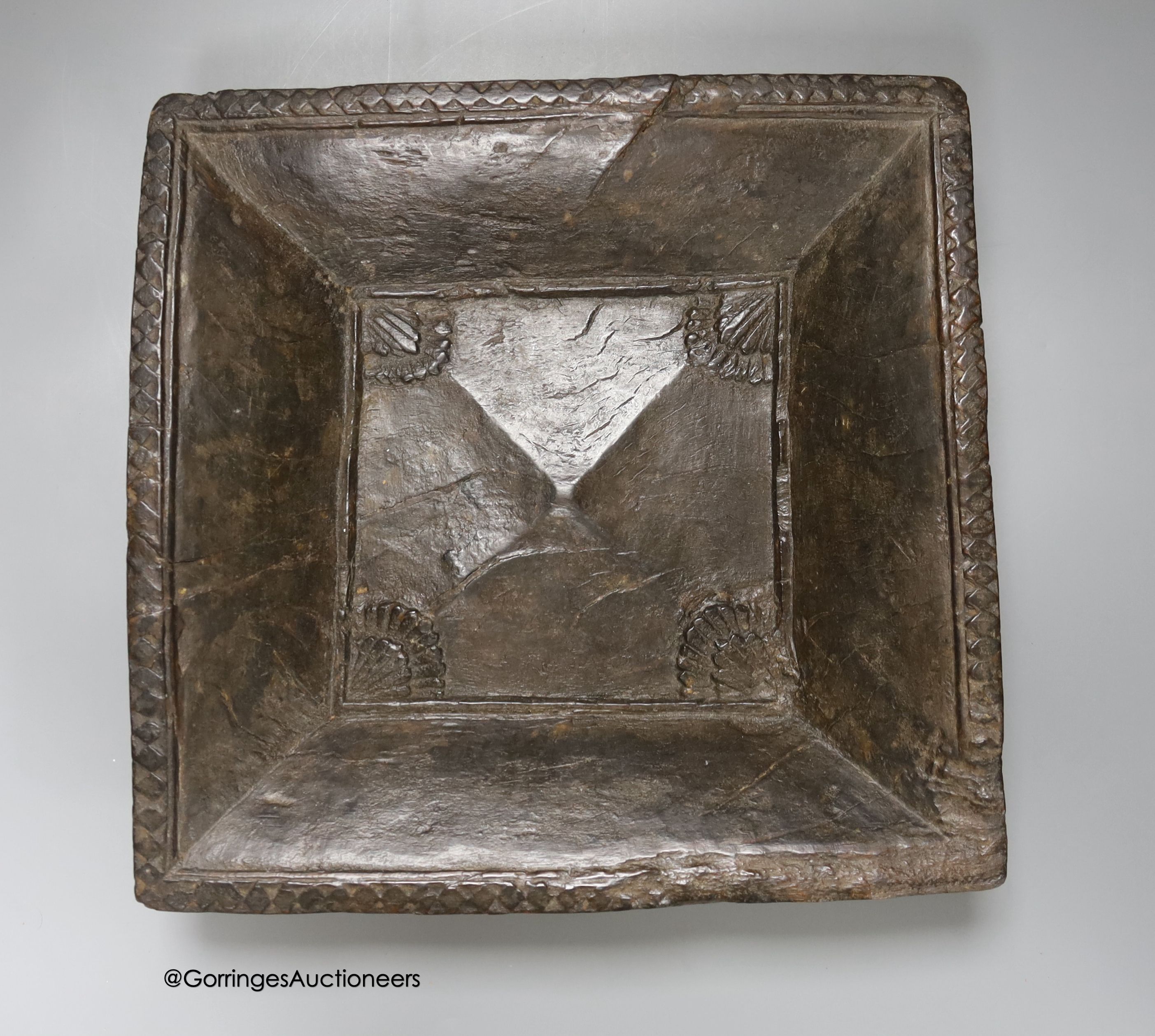 An early square wood tray, carved from the solid, possibly Spanish chestnut, 30cm, and a pair of Indian light wood stands